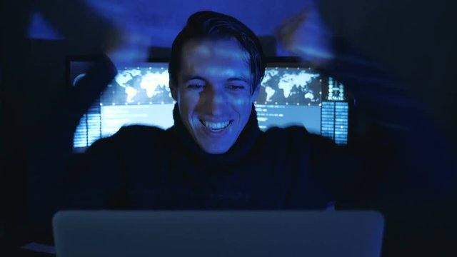 Portrait of Amazed Surprised Professional IT Programmer in a data center filled with monitor screens. Sudden Victory or Success