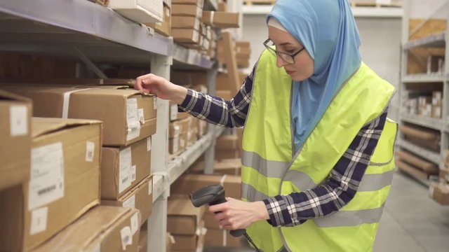 Muslim in hijab store worker conducts accounting using barcode scanner