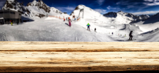 Wooden desk space and winter landscape of mountains in Alps 