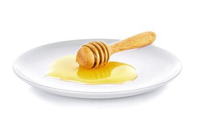 Wooden honey dipper with honey white plate on white background