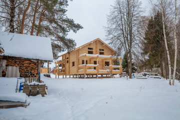 view of a wooden house under construction with forest, winter