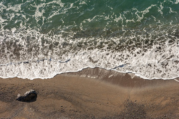 Aerial view of sandy beach and sea with waves