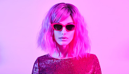 Sexy woman in party bright luxury outfit. High Fashion. Model girl with pink blonde dyed hair, makeup. Colorful neon light. Night Clubbing art style