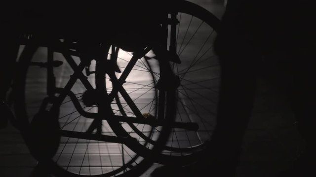 Rear view of silhouette of woman pushing disabled man on wheelchair along hallway of retirement home