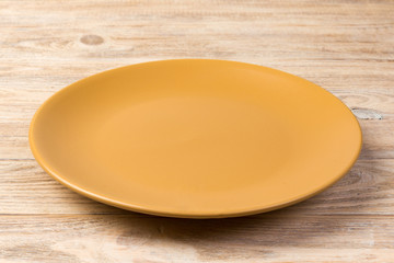 Perspective view. Empty orange matte dish for dinner on orange wooden background