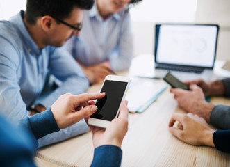 Group of young businesspeople with smartphone having meeting in office. Copy space.