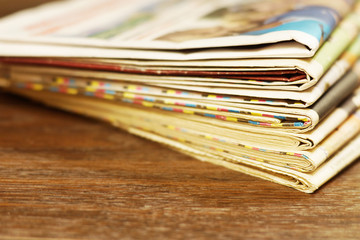 Pile of fresh morning newspapers on the table at office. Latest financial and business news in daily paper. Pages with information (headlines, articles, photos, text). Folded and stacked journals    