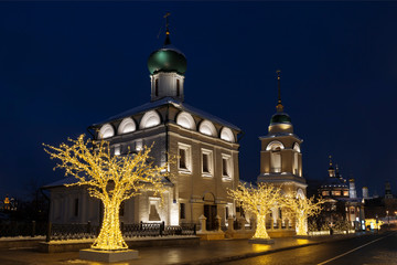 Fototapeta na wymiar Varvarka street with churches of St. Barbara with bell tower and Maxim the Confessor (Maxim the blessed) at Christmas and New year's in the evening. Moscow, Russia