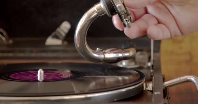 Man preparing vintage gramophone and playing a vinyl record, retro style concept.