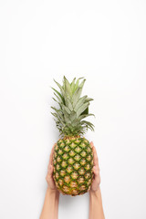 cropped view of woman holding pineapple in hands isolated on white