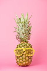 funny and tasty pineapple in sunglasses on pink background