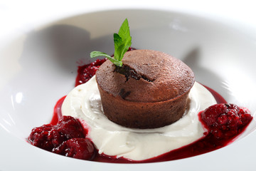 Czekoladowa muffinka  podana z bitą śmietaną i sosem wiśniowym.