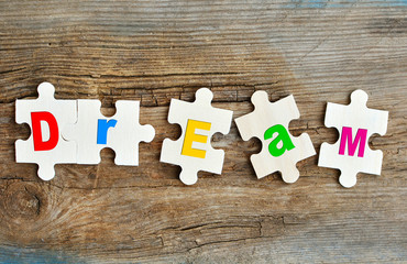 Dream concept. Puzzles with letters on a wooden background. Concept of building dream.