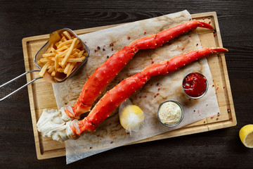 Cooked king crab legs with sauces and french fries © Prostock-studio