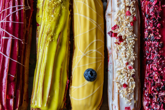 Group of french dessert Eclair cake with white yellow and red creme and shining decoration