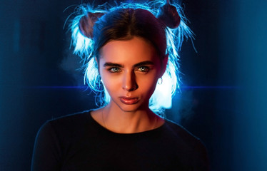 Close-up portrait of an angry angry girl in the studio on a dark background with neon backlight