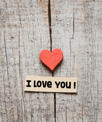 I love you text on a wooden background with a red heart.