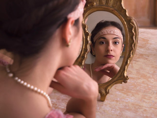 Dreamy woman in 1920s headband with mirror