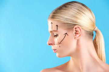 Beautiful Woman Face. Beauty Portrait of young woman blond, painted lines on the face for cosmetic surgery on blue background. Cosmetic surgeon blepharoplasty. Lifting