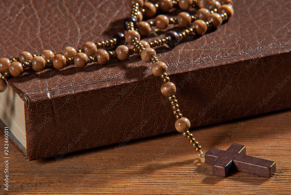 Wall mural Book with rosary on the wooden table.