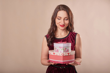 young attractive girl with gifts on a beige background on Valentine's Day February 14