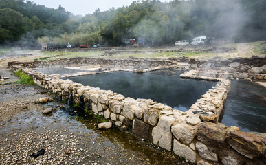 Natural Roman baths outdoors with hot steam and thermal water.