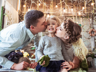 happy parents kissing their five year old daughter