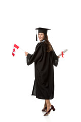 smiling female student in academic gown holding canadian flag and diploma isolated on white
