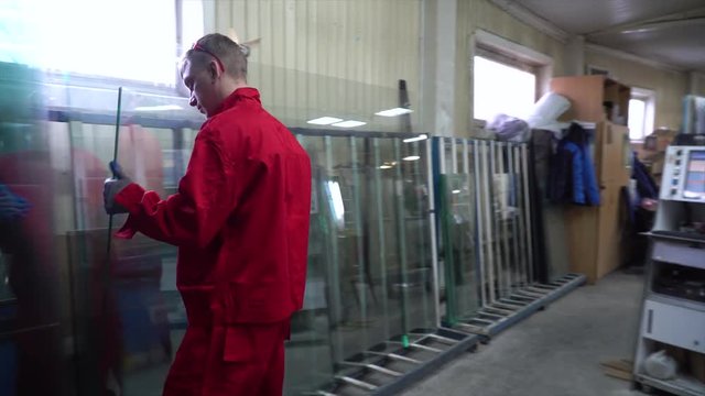 Manufacture of plastic windows and doors. Worker fastens the fittings with a screwdriver to the plastic window in the shop for the production of plastic and metal windows and doors. Screwing screws.
