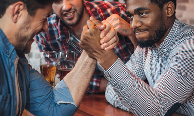 Male friends arm wrestling each other in bar