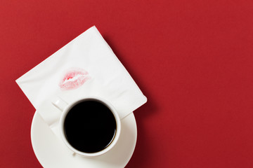 paper napkin with a kiss and coffee cup on red background.