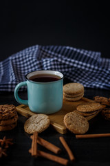 Cup of tea and various cookies on dark wooden background