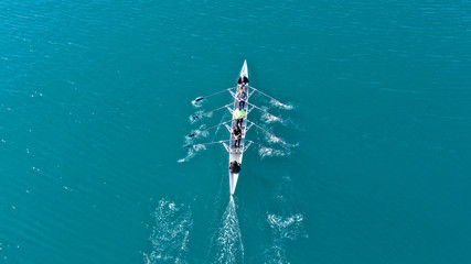 Aerial drone bird's eye view of sport canoe operated by team of young men in open sea