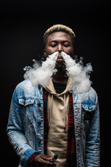 Young handsome african man smoke vape isolated on dark background