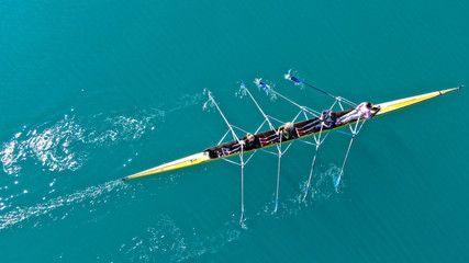 Aerial drone bird's eye top down view of sport canoe operated by team of young men in open sea