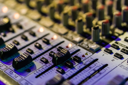 Selective focus on knops of electronic sound mixer in the foreground of the outdoor party music