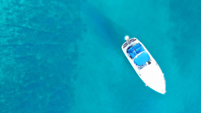 Aerial top view of boat in tropical sapphire clear waters