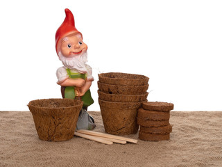 Coir plant pots and compressed compost with wooden labels and generic garden gnome. Environmentally...