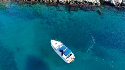 Aerial bird's eye view photo taken by drone of boat cruising in caribbean tropical beach with turquoise - sapphire waters