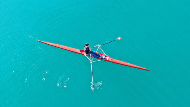 Aerial drone bird's eye view of sport canoe operated by young fit man in turquoise clear waters