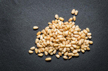 Close up. Top view. A handful of nutritious pine nuts on black background. Copy space.