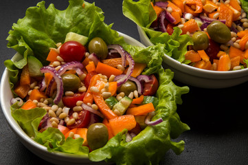 Close up. Vegan food. Vegan greek salad with tofu and pine nuts. Black background.