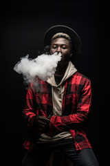 African Man smoking or vaping e-cig or electronic cigarette holding a mod with a lot of clouds...