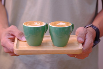 Fototapeta na wymiar Man hand holding a green cup of Hot cappuccino coffee.
