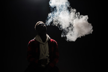 Close up of a african man holding an electronic cigarette isolated on a black background