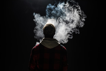 Close up of a african man holding an electronic cigarette isolated on a black background