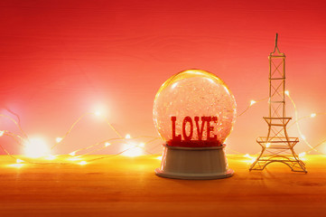 Valentine's day background. Water globe with word LOVE and glitter over the wooden table and pink...