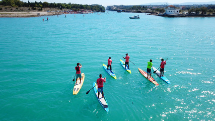Aerial photo of colourful sport canoes in competition as shot from above in turquoise clear waters