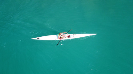 Aerial drone bird's eye view of sport kayak operated a young men in tropical exotic turquoise clear ocean
