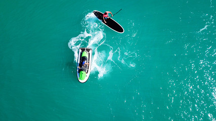 Aerial top view of jet-ski cruising in low speed in mediterranean emerald clear waters